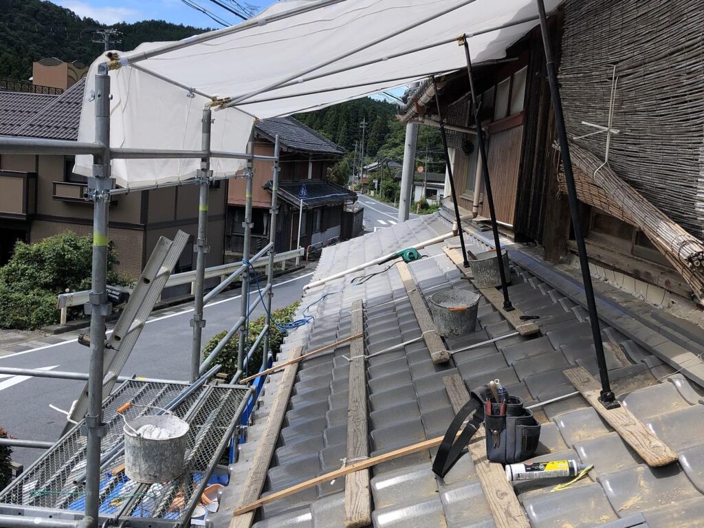 瓦屋根の上に設置されたBase101庇用商品による日除けシートと足場の様子