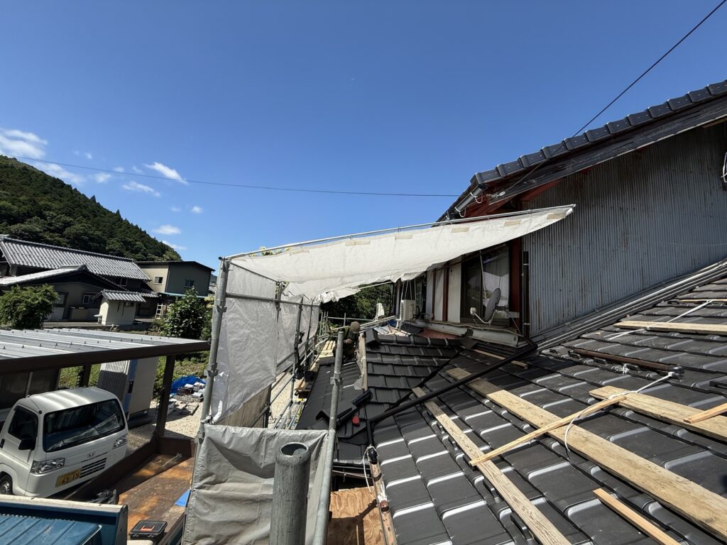 仮設足場に雨よけ・日よけシートを設置した屋根工事現場の暑さ・雨対策の様子