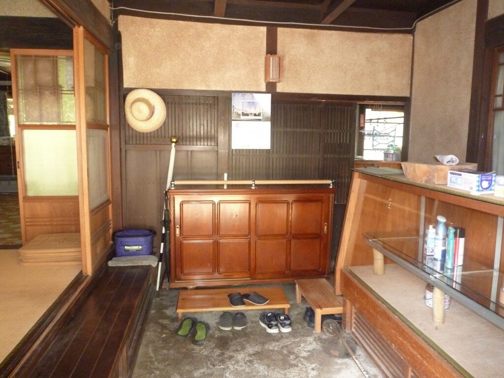 多賀町大杉の中古住宅の玄関内。木製の下駄箱と飾り棚、和室への入口が見える。