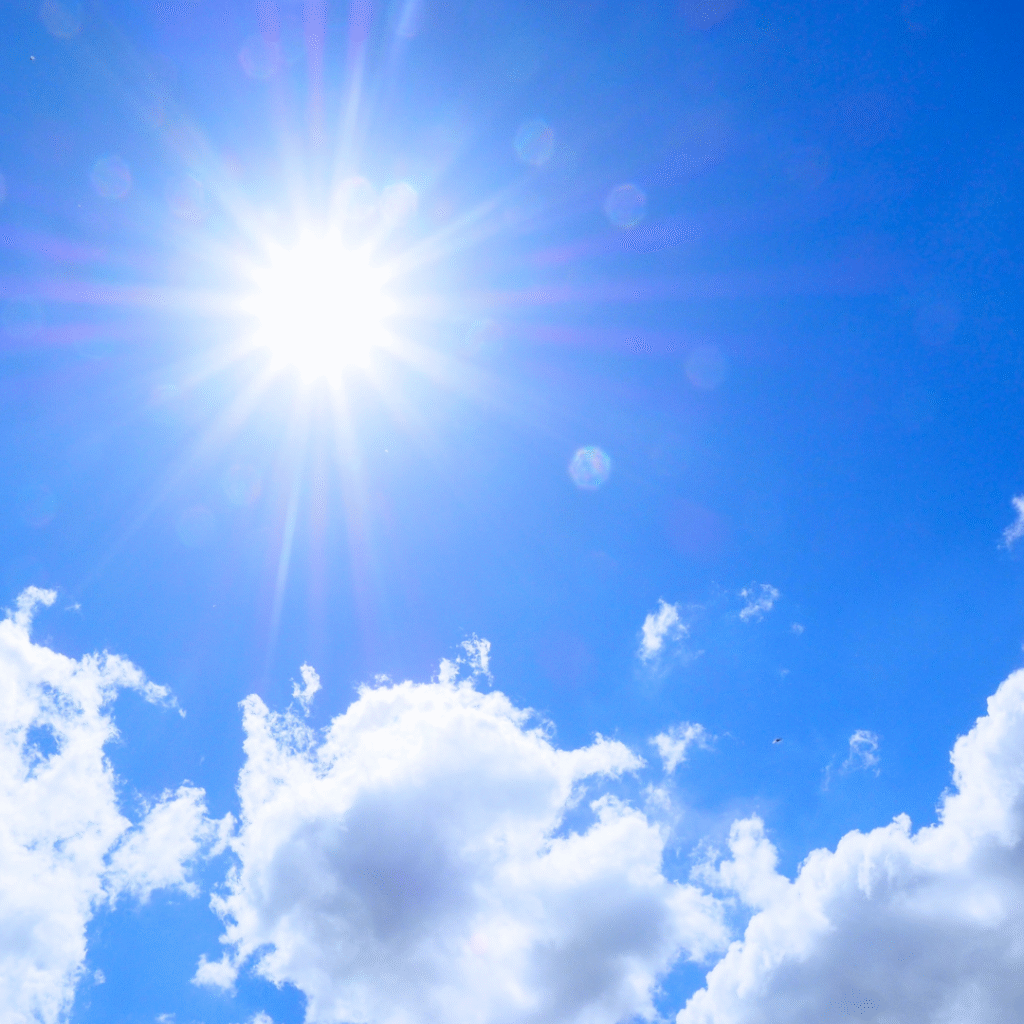 青空に輝く太陽の光。力強さとエネルギーを象徴するイメージ。