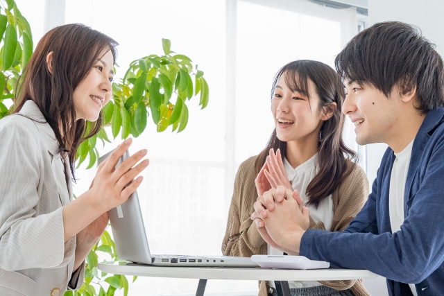 太陽光発電の導入について相談する若い夫婦と担当者