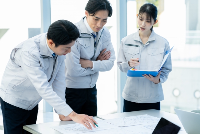 建設現場の環境改善について図面を確認するスタッフの打合せ風景